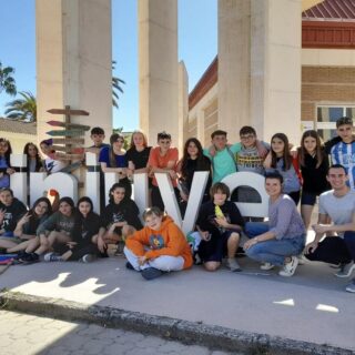 Grupo de alumnos juntos posando para una foto junto a una estructura con letras
