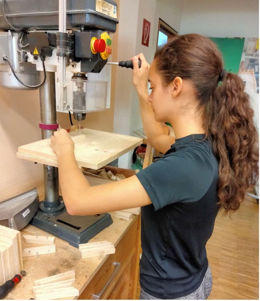 Niña tallando en madera con un fresador